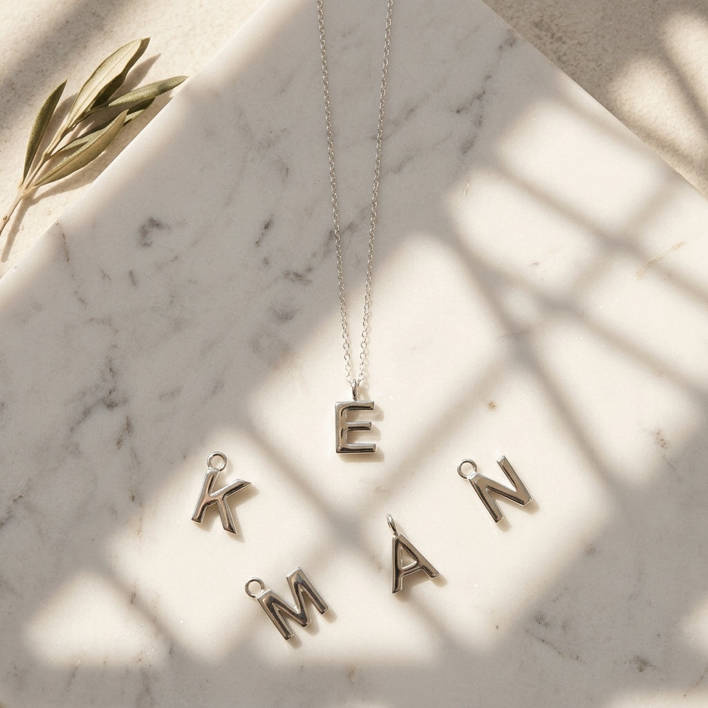 Necklace with letter pendants on a marble surface with leaf decoration