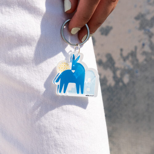Keychain with blue donkey design held by a hand against a white background