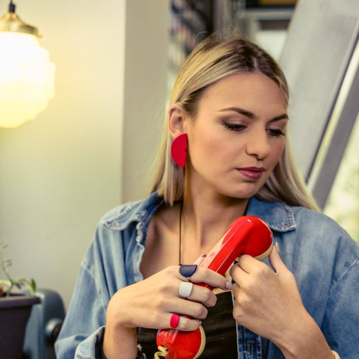 Woman holding a red hair dryer in an indoor setting