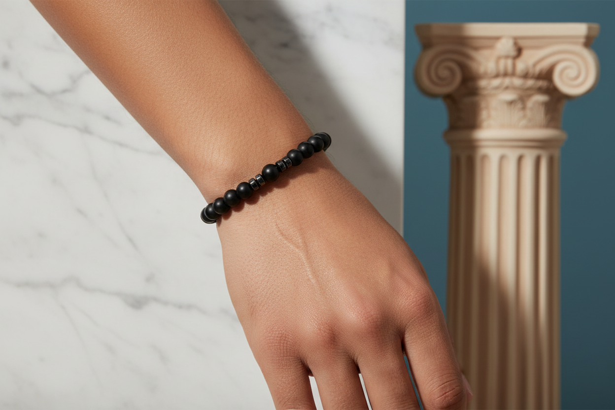 Hand wearing a black beaded bracelet with a classical column in the background
