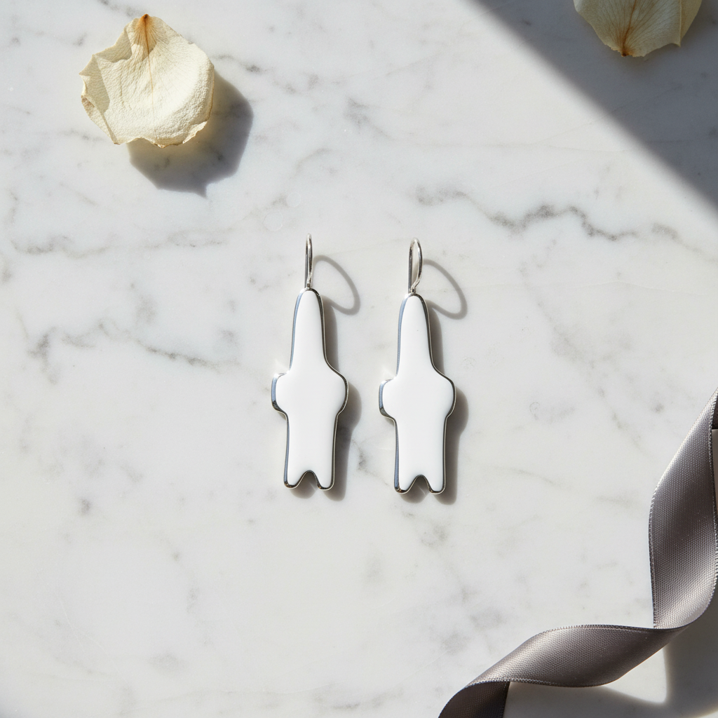 Silver abstract earrings on a marble surface with a white rose.